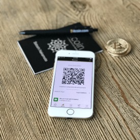 iPhone with Bitcoin wallet and qr code on the screen with bitcoin pen, coin, booklet in background
