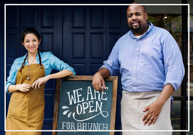 cheerful-business-owners-standing-with-open-PK4BF57