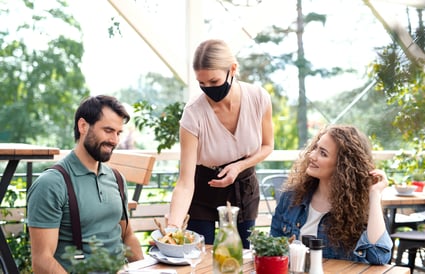 waitress-with-face-mask-serving-happy-couple-outdo-NNLJBR8