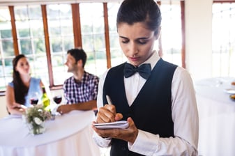 waitress-writing-order-on-notepad-in-restaurant-5CTVN5E